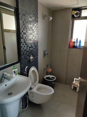 Bathroom features a sink, toilet, and shower area with a mosaic tile pattern and a mirror above the sink.