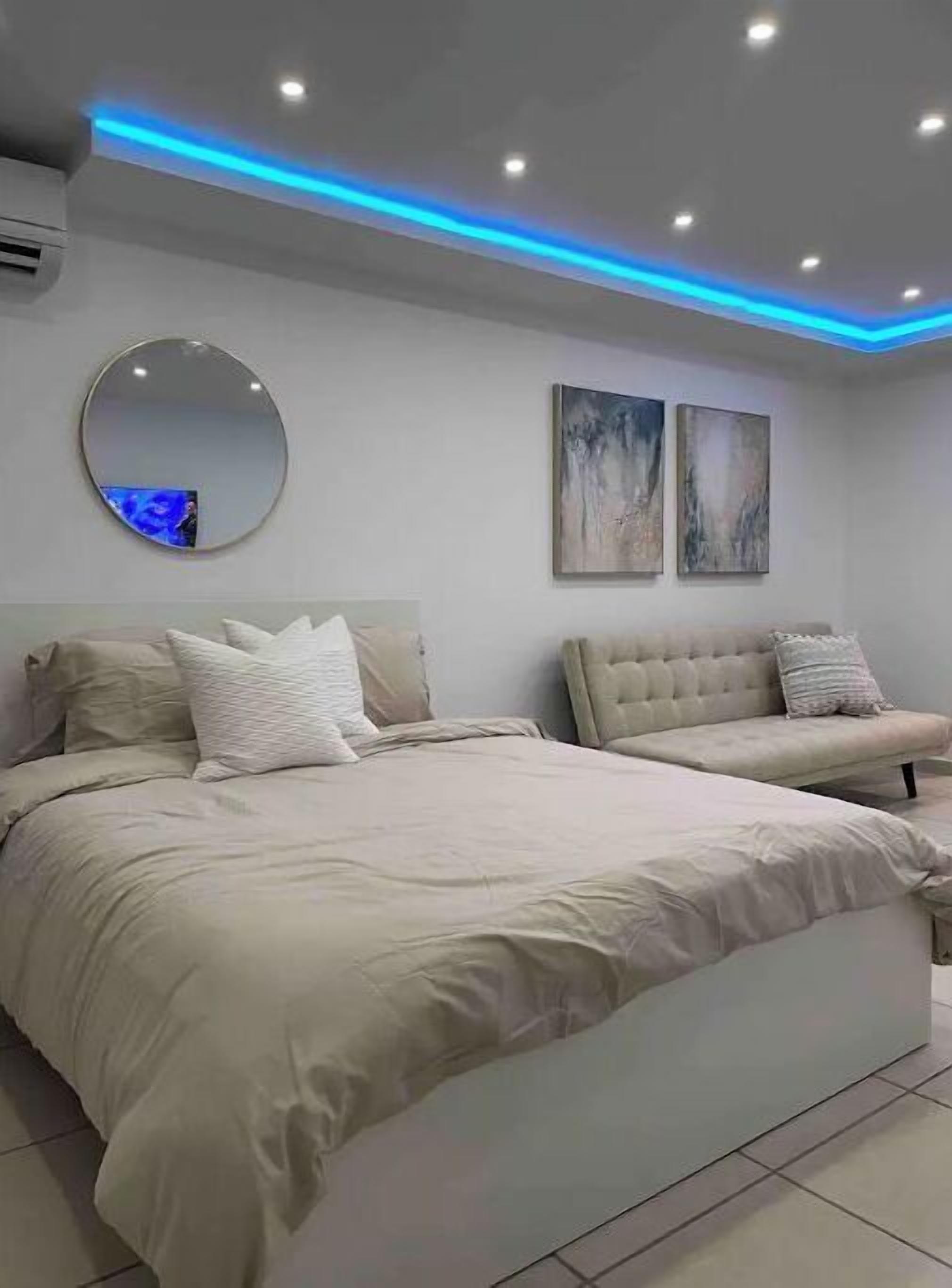 Une chambre à coucher moderne avec un grand lit, un miroir rond et deux œuvres d’art accrochées au mur.