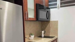 A compact kitchen with a stainless steel refrigerator, a microwave, and a sink. - Brand New Modern Studio with Pool (Luquillo)