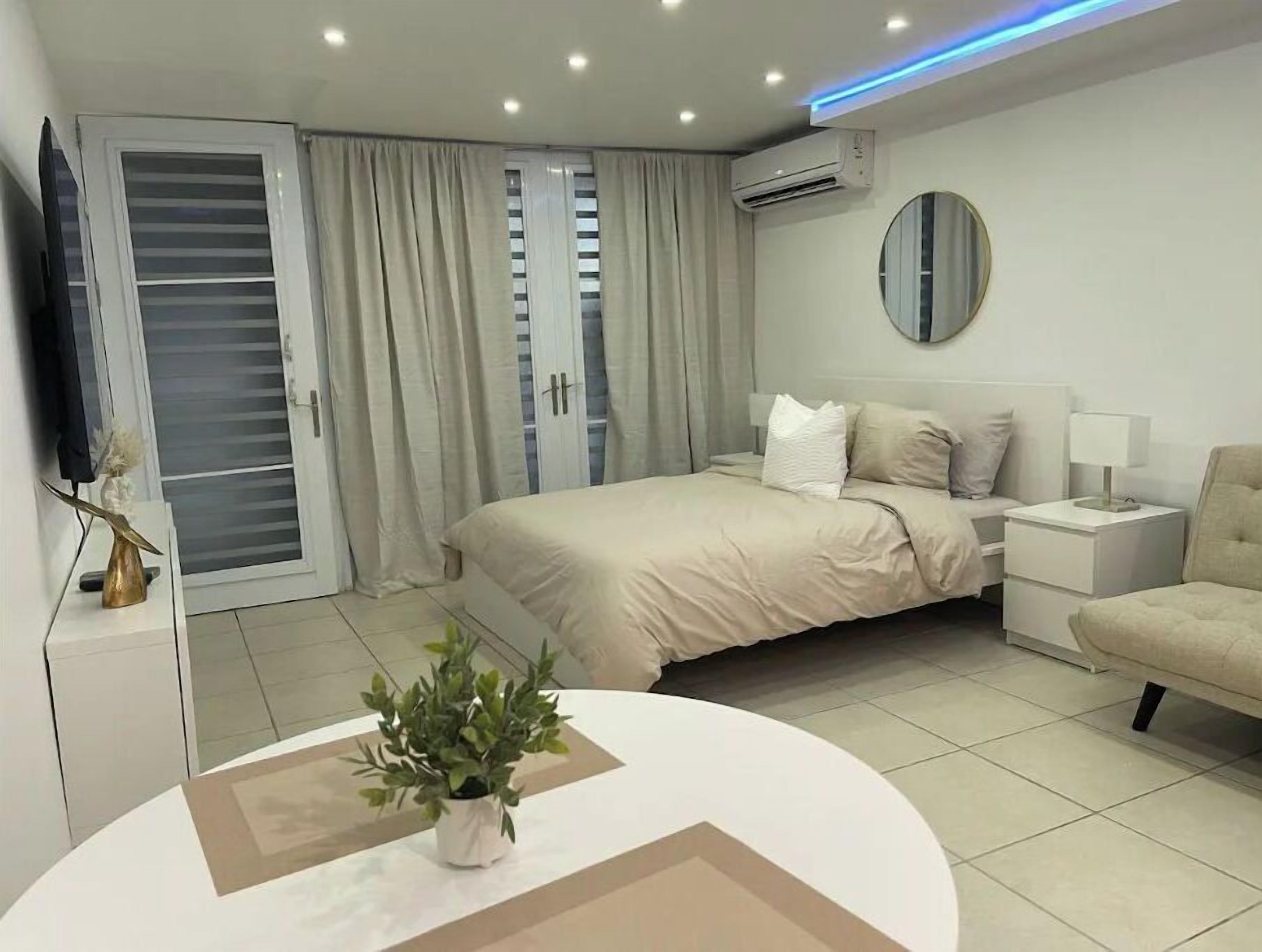 Une chambre à coucher moderne avec un lit, des tables de chevet, un miroir et une plante en pot.