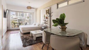 A modern living room with a sofa, a glass table, and a large window overlooking a cityscape. - Departamento moderno (Buenos Aires)