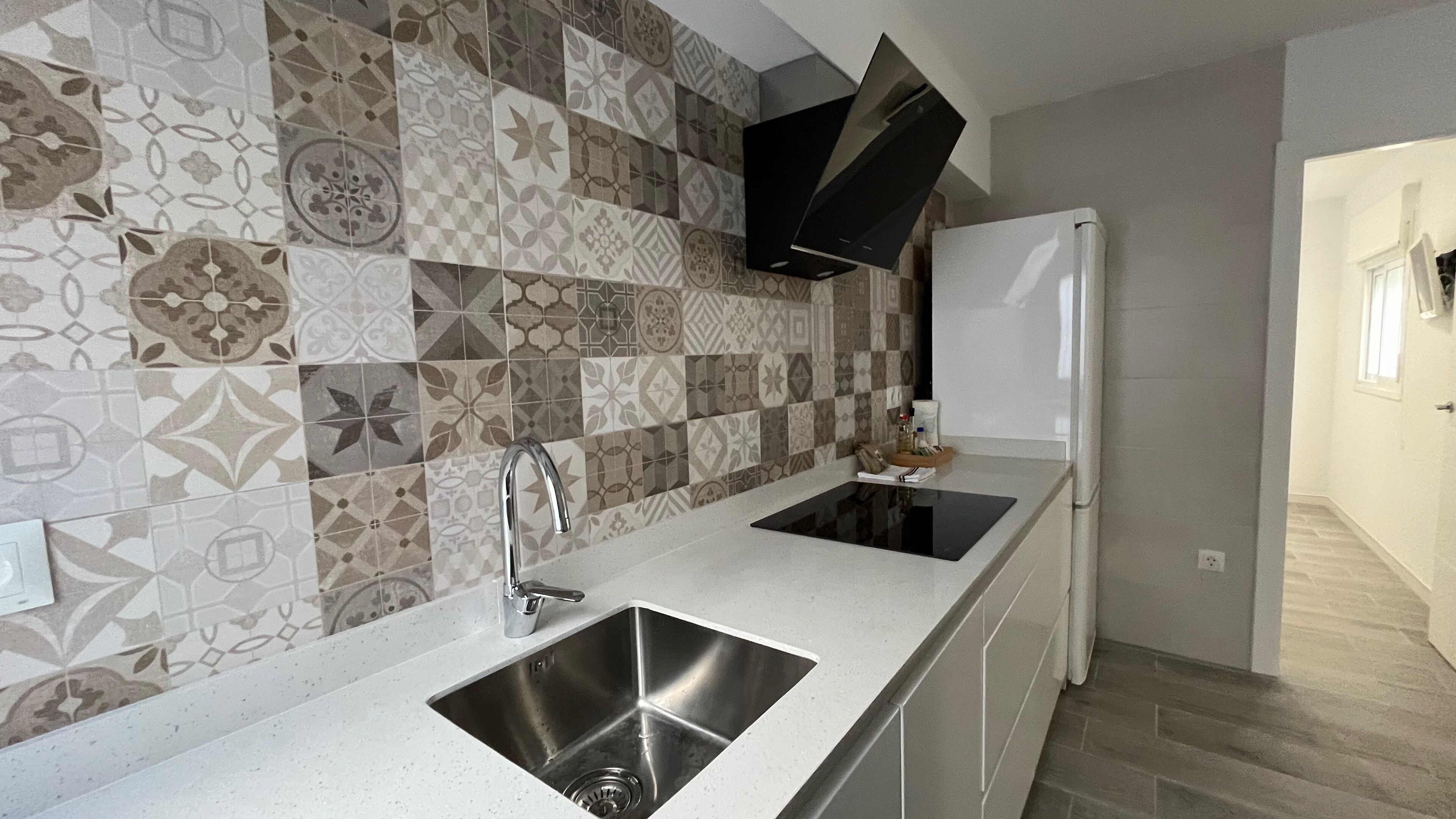A kitchen with a modern design, featuring a stainless steel sink and a built-in stove.