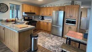 A modern kitchen with wooden cabinets, stainless steel appliances, and a central island. - Elephant Lake Summerset Oasis New (Elephant Butte)