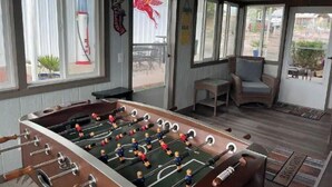 A room with a foosball table, a chair, and a window with a view of the outside. - Elephant Lake Summerset Oasis New (Elephant Butte)