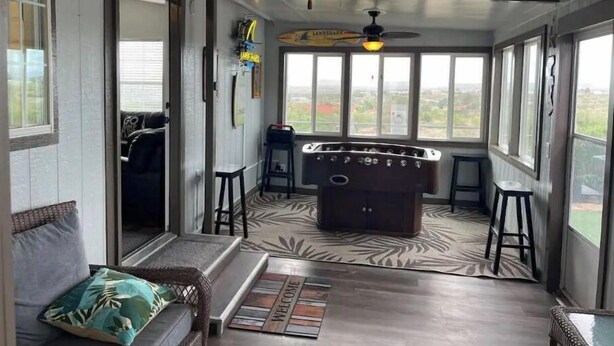 A room with a pool table, a sofa, and a bar area with stools. - Elephant Lake Summerset Oasis New (Elephant Butte)
