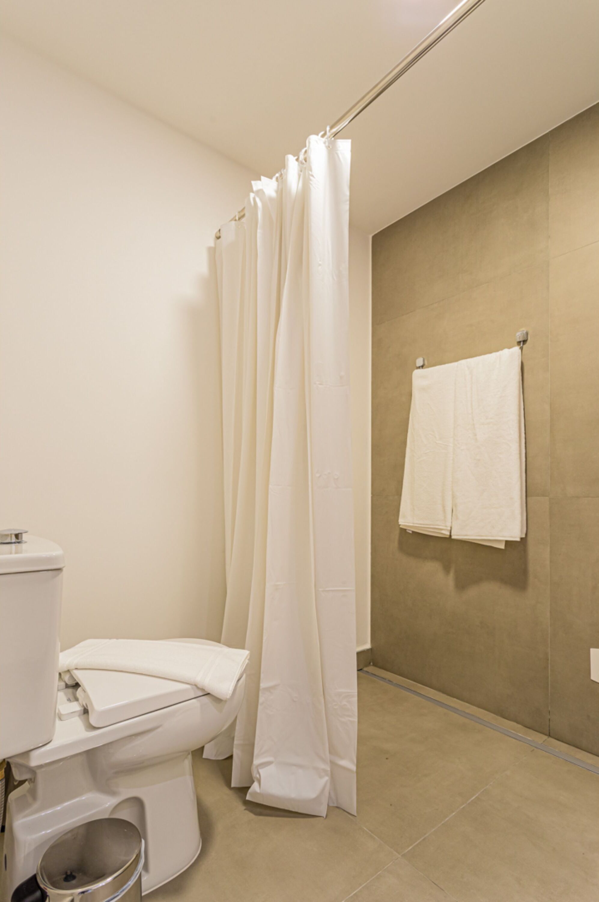 Un bagno con il water, una tenda della doccia e un asciugamano appeso al muro.