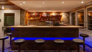Eine Bar mit einer zentralen Theke, Hockern und Regalen voller Flaschen.