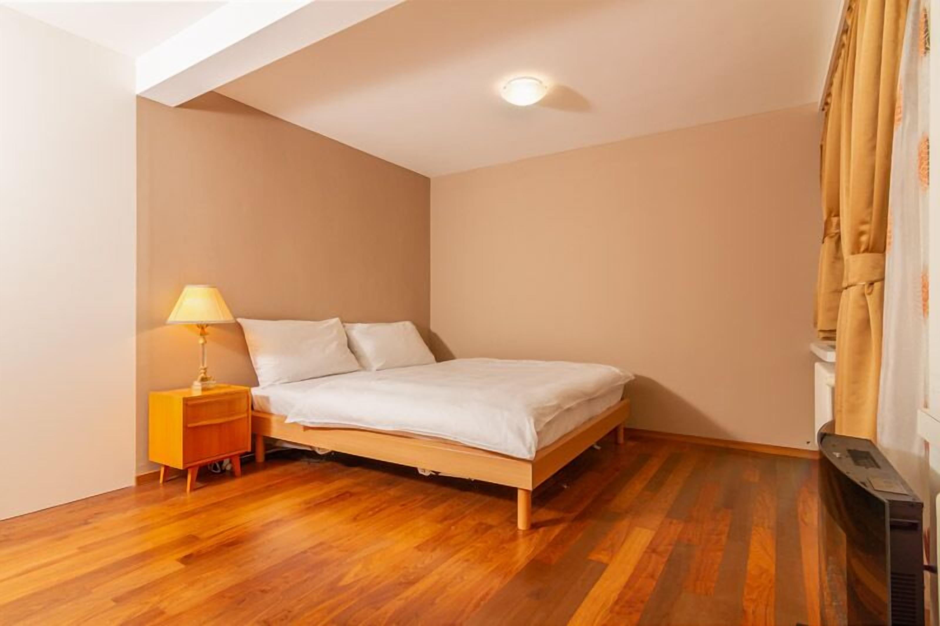 Ein Schlafzimmer mit einem Bett, einem Nachttisch, einer Lampe und einer Deckenleuchte.