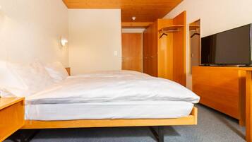 Un lit simple avec un cadre en bois et une literie blanche, dans une pièce dont le plafond et les murs sont en bois.