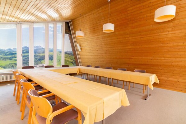 Un salón de conferencias con una larga mesa, sillas y vistas al campo.