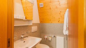 A small bathroom with a wooden wall, a white sink, and a toilet.