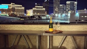 A bar area with stools and a bottle of champagne on a coaster, overlooking a cityscape at night. - Lovely 2BR/2BA Condo 1mi From Strip w/ Views!
 (Las Vegas)
