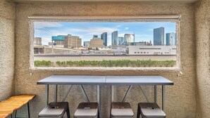 A room with a large window overlooking a cityscape, a table, and three stools. - Lovely 2BR/2BA Condo 1mi From Strip w/ Views!
 (Las Vegas)
