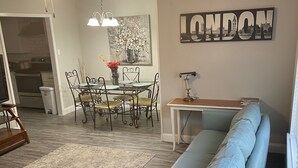 A living room with a blue sofa, a dining table with chairs, a ceiling fan, and a wall-mounted artwork with the word "LONDON". - NEAR TX A&M, HWY 6 , NO CLEANING FEE ,ENTIRE PLaCE (College Station)