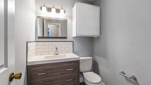 A bathroom with a white toilet, a vanity with a mirror, and a cabinet above the mirror. - NEAR TX A&M, HWY 6 , NO CLEANING FEE ,ENTIRE PLaCE (College Station)