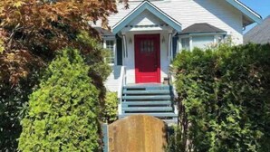 A two-story house with a red door, a front porch, and a wooden gate. - Quiet and cosy get away suite in Point Grey Vancouver BC, near UBC and beach. (Vancouver)