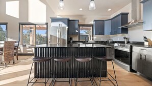 A modern kitchen with a large island, bar stools, stainless steel appliances, and blue cabinets. - Valley Vista Retreat - New 5BR Cabin (Lead)
