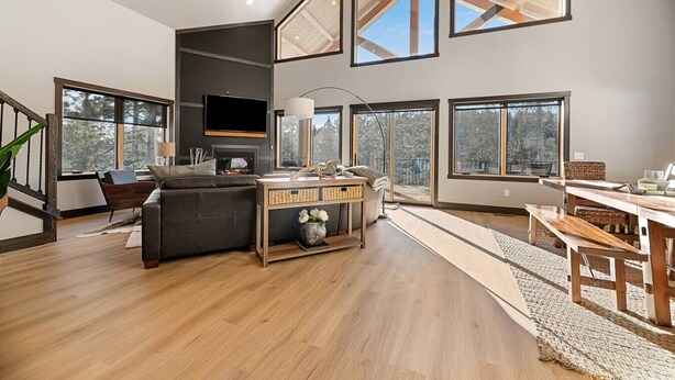 A spacious living area with a fireplace, large windows, and a dining area with wooden furniture. - Valley Vista Retreat - New 5BR Cabin (Lead)