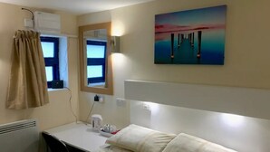 Et hotelværelse med en seng, et natbord og et billede på væggen.