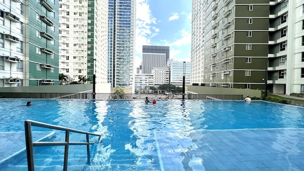 An indoor swimming pool with clear blue water, surrounded by high-rise residential buildings.