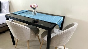A dining table with a blue tablecloth, two chairs, and a vase with flowers.