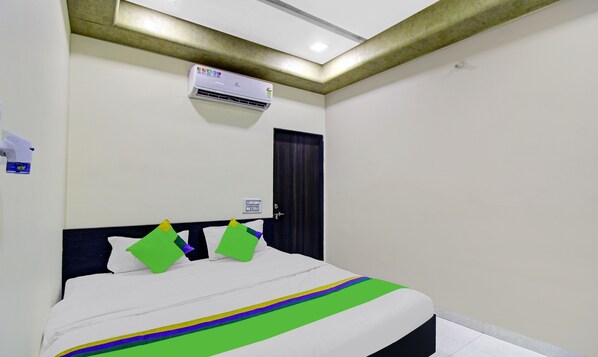 Quarto de hotel com cama, ar condicionado, porta e tomada.
