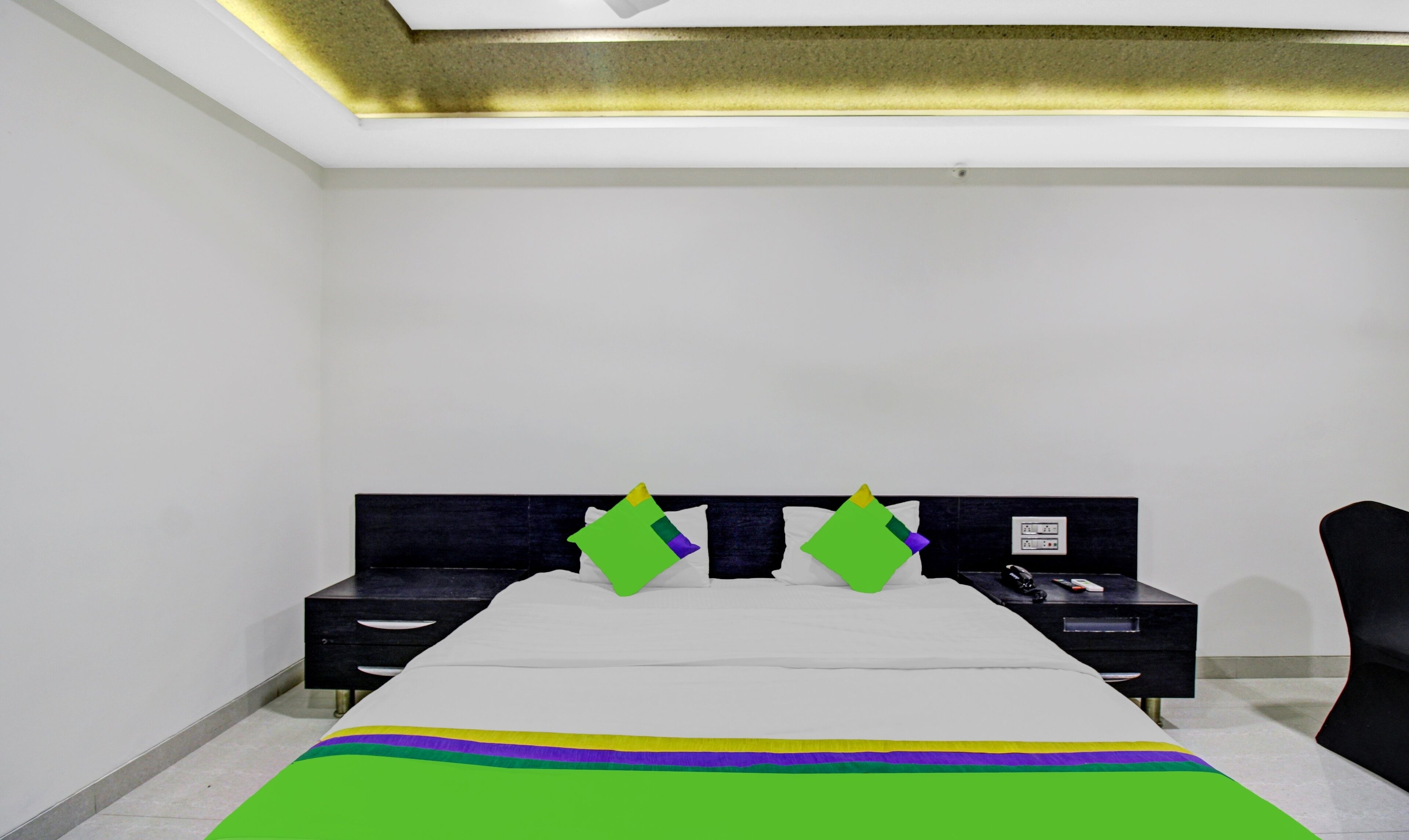 A bedroom with a bed, two nightstands, a chair, and a ceiling light fixture.