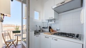 A modern kitchen with white cabinets, a gas stove, and a window overlooking a balcony. - Porcellana Apartment (Firenze)