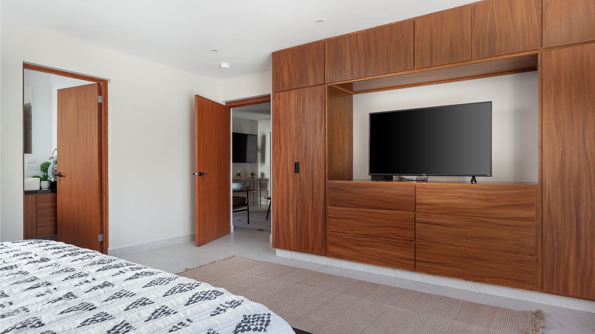 A bedroom with a bed, a TV, and wooden furniture.