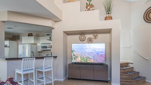 A modern living room with a flat-screen TV, white chairs, a coffee table, and a staircase with patterned steps. - Beautiful Cave Creek 3 Bdrm home in Quiet Area! (Cave Creek)