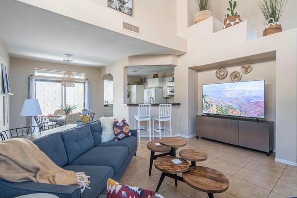 A modern living room with a gray sofa, a coffee table, and a TV on a cabinet. - Beautiful Cave Creek 3 Bdrm home in Quiet Area! (Cave Creek)
