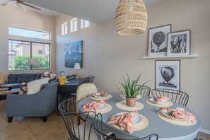 A modern living room with a grey sofa, dining table with placemats, and a potted plant. - Beautiful Cave Creek 3 Bdrm home in Quiet Area! (Cave Creek)