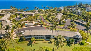 An aerial view of a resort with multiple buildings, palm trees, and a view of the ocean. - Tropical Oasis - Stunning Views In Private Setting (Princeville)