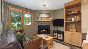 A living room with a fireplace, leather sofa, wooden coffee table, and a bookshelf.