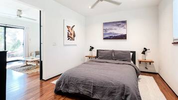 A modern bedroom with a large bed, a ceiling fan, and artwork on the walls.