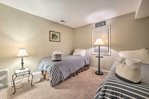 Une chambre avec deux lits, une table de chevet, une lampe, un radiateur et un panneau décoratif mural.