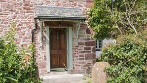 A stone building with a wooden door and a small porch.