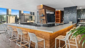 A modern kitchen with a central island, bar stools, and a view of the cityscape. - Pool, Views 1BR Downtown Condo near Bayfront Park (Miami)