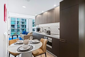 A modern kitchen with dark cabinets, a white countertop, and a dining area with a table set for two.