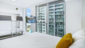 Une chambre d’hôtel moderne équipée d’un lit, d’une télévision, d’une fenêtre donnant sur la ville et d’un balcon.