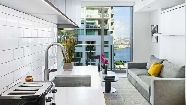 Une cuisine moderne avec vue sur un immeuble de grande hauteur et un balcon.