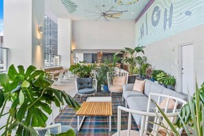 Un espacio interior moderno con asientos, plantas y un ventilador de techo.