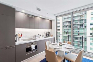 A modern kitchen with grey cabinets, a white countertop, and a dining area with a round table and chairs.