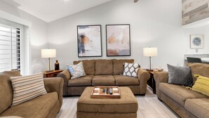 A modern living room with a brown sofa set, two side tables with lamps, and abstract wall art. - Luxurious Fairway Condo Resort (Palm Desert)