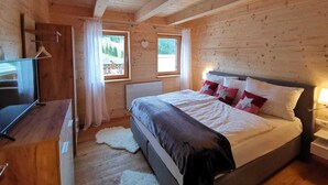 Une chambre dans une cabane en bois, avec un lit, une télévision et deux fenêtres.