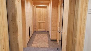 Un couloir en bois, avec un sol carrelé et une porte au fond.