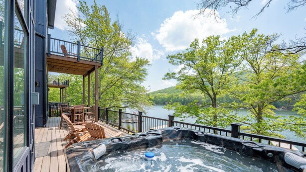 Un jacuzzi en una terraza de madera con vista a un lago y árboles.