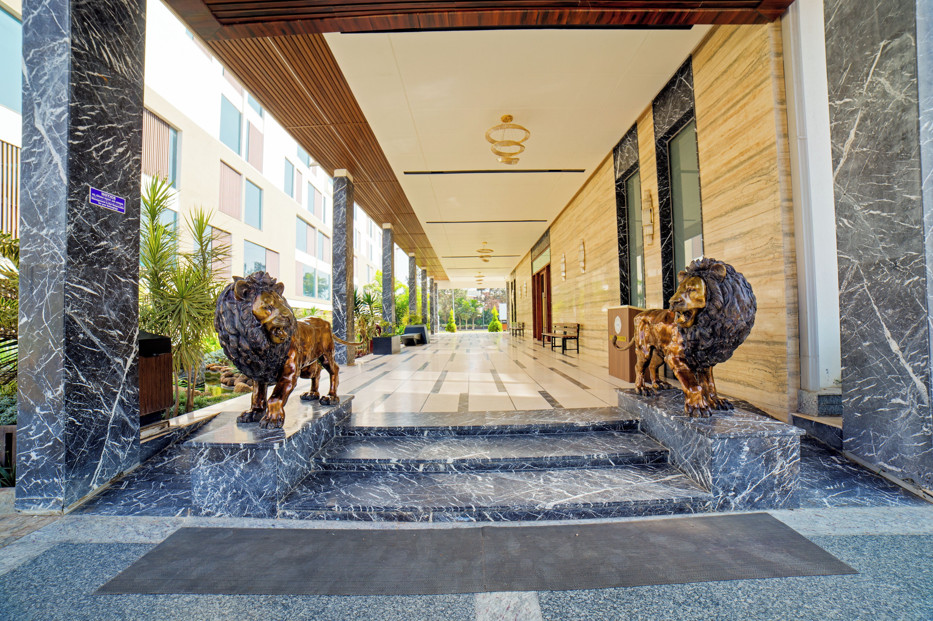 Un vestíbulo de hotel con escalones de mármol, dos estatuas de leones y un techo de madera.