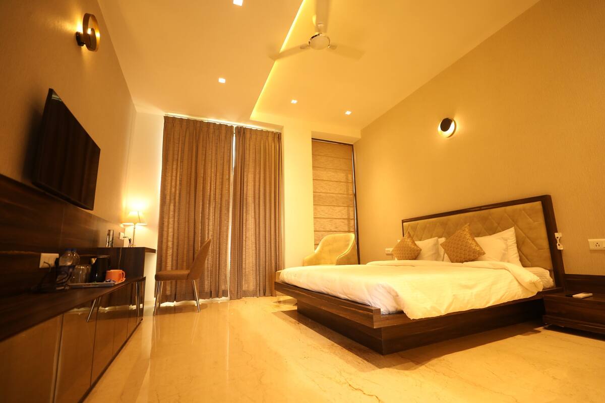 A hotel room with a bed, a desk with a chair, a TV, and a ceiling fan.