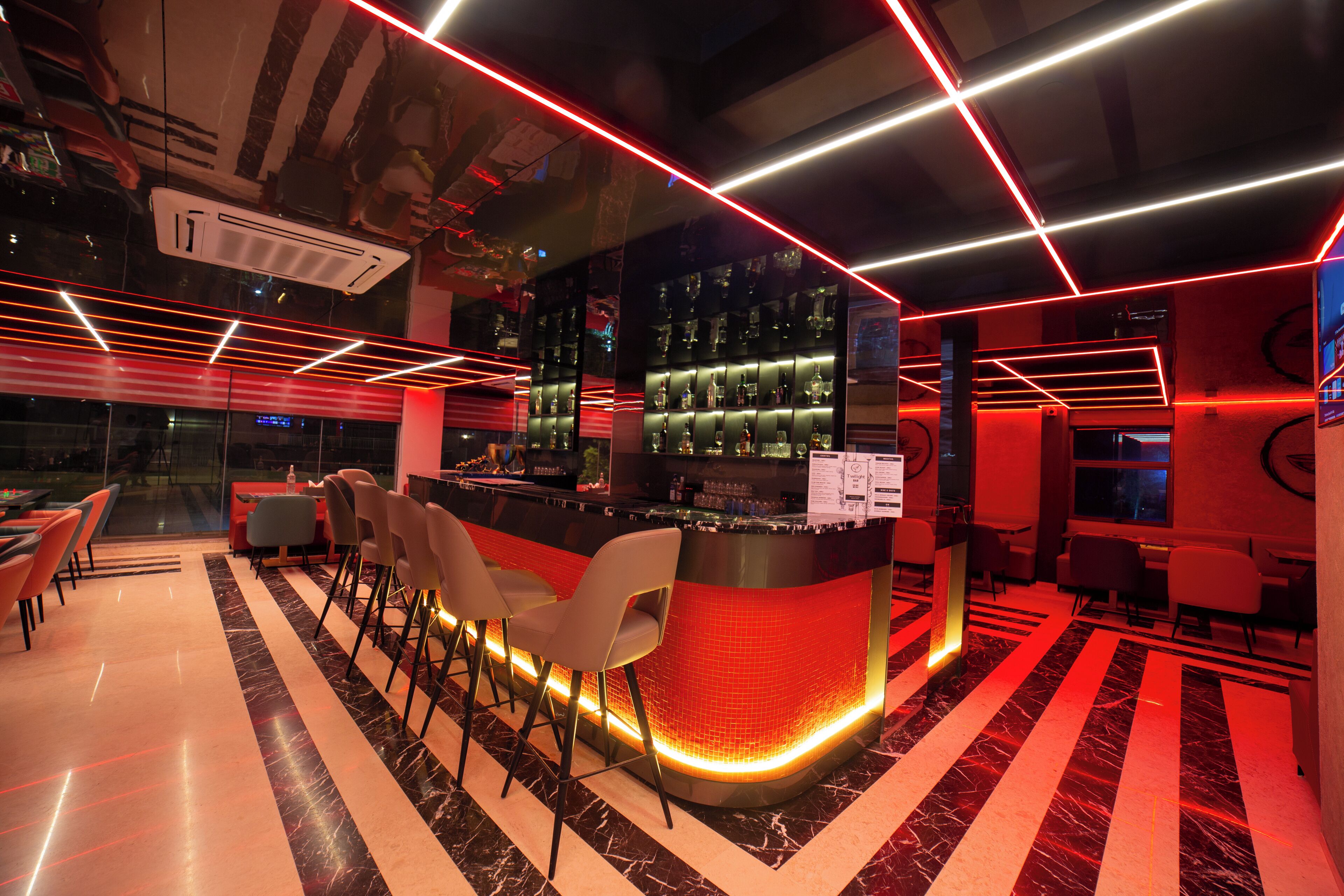 A bar area with a counter, bar stools, and a red neon light design.
